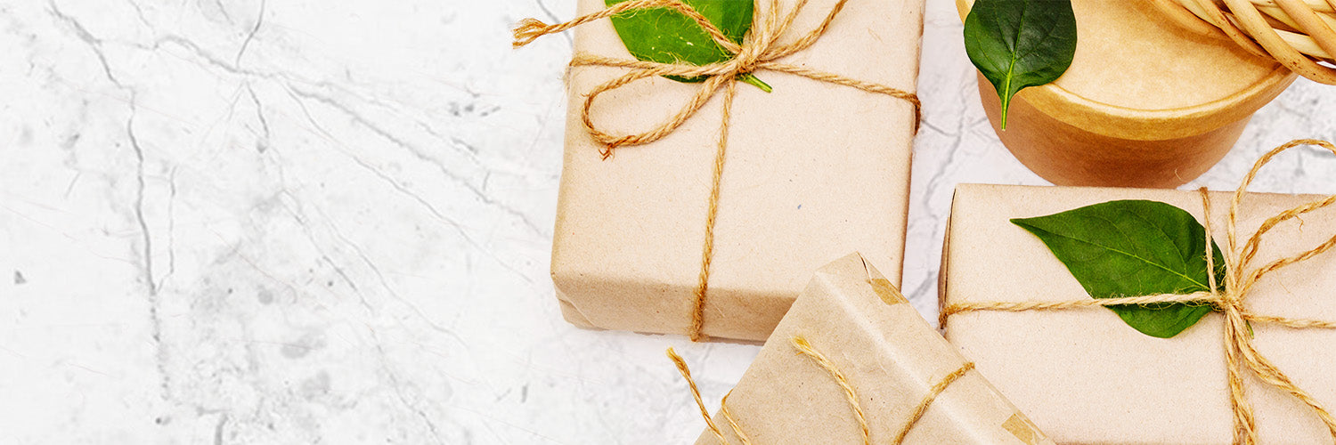 gifts wrapped in brown paper with leafs on top on a marble background